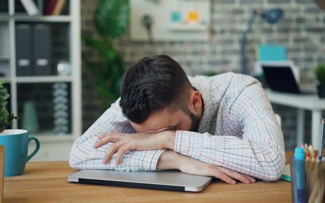 Hombre agotado con la cabeza apoyada sobre el escritorio
