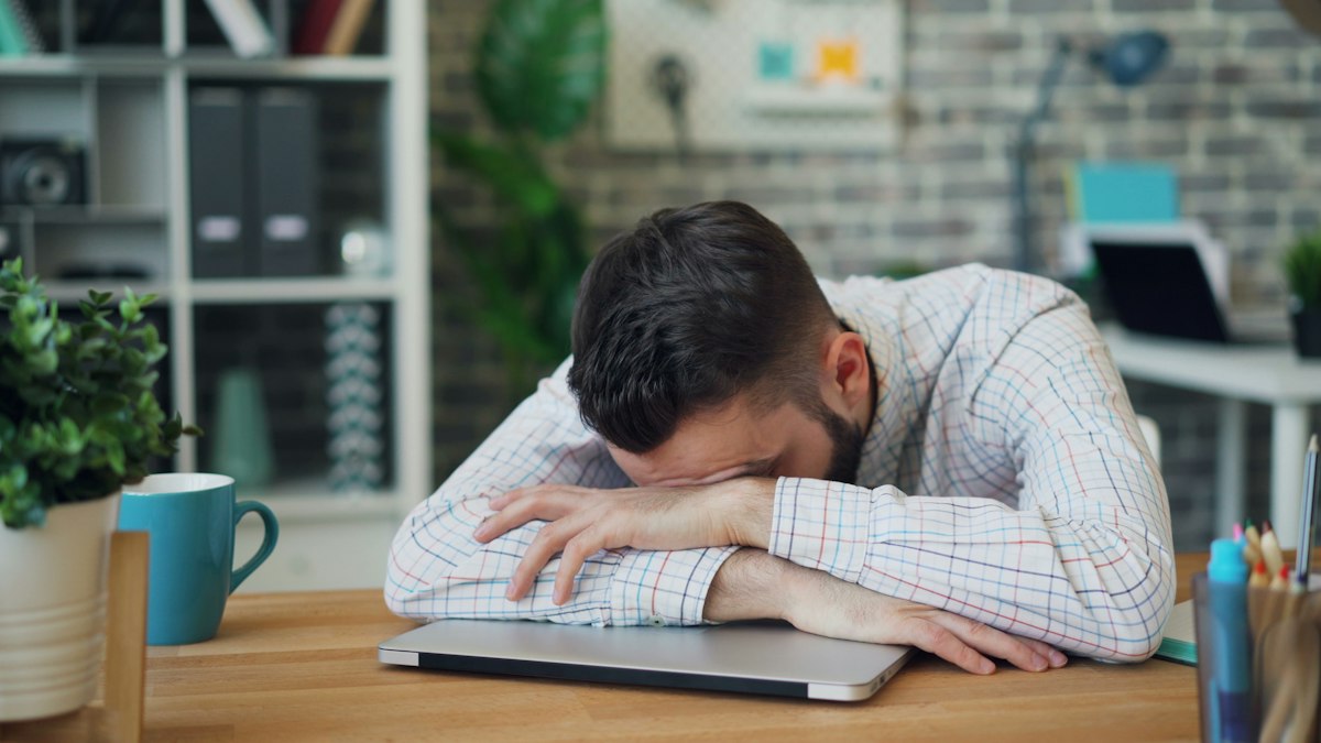 Hombre agotado con la cabeza apoyada sobre el escritorio